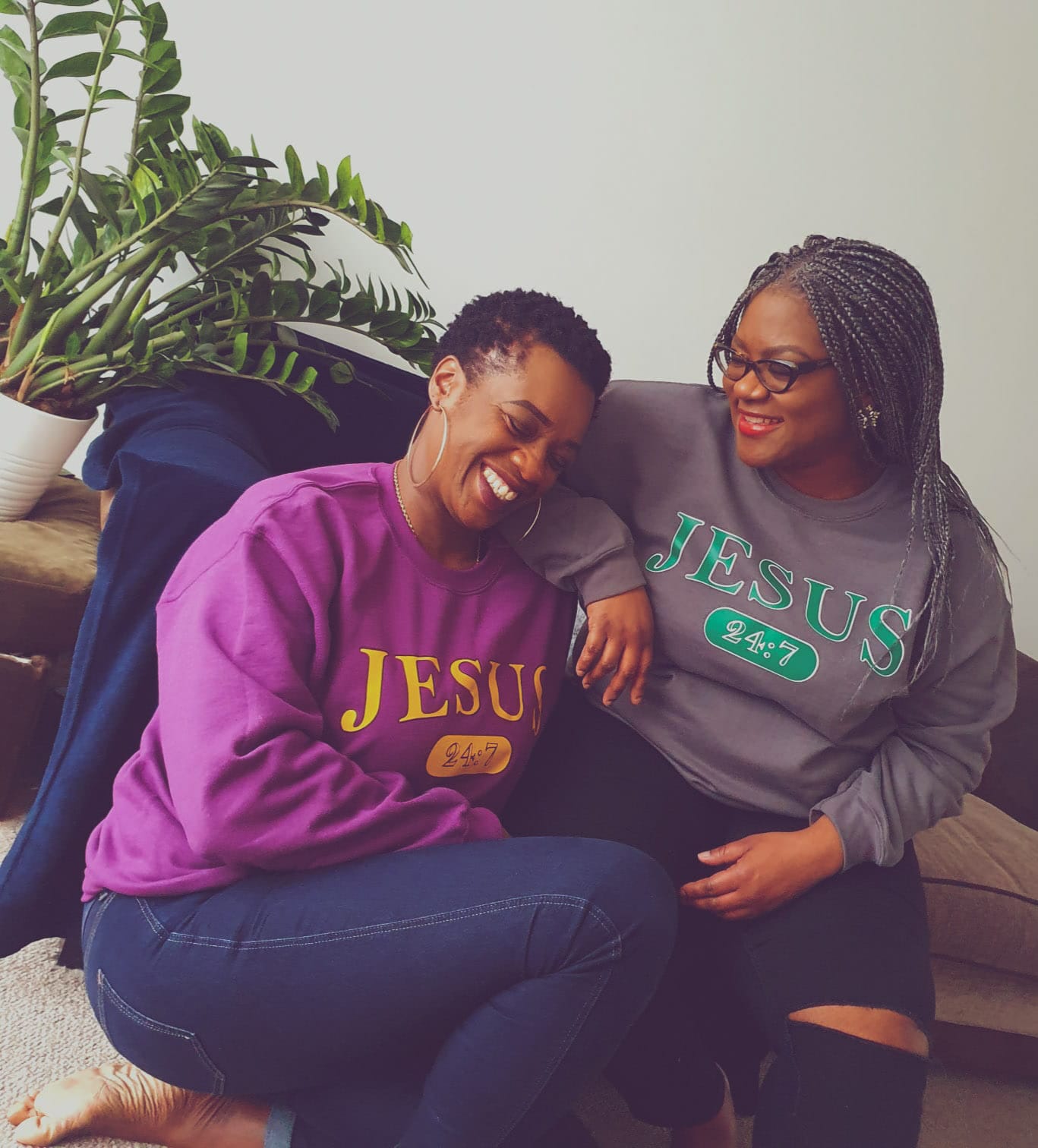 Two women enjoying each others company laughing, whilst wearing a Jesus printed sweatshirt
